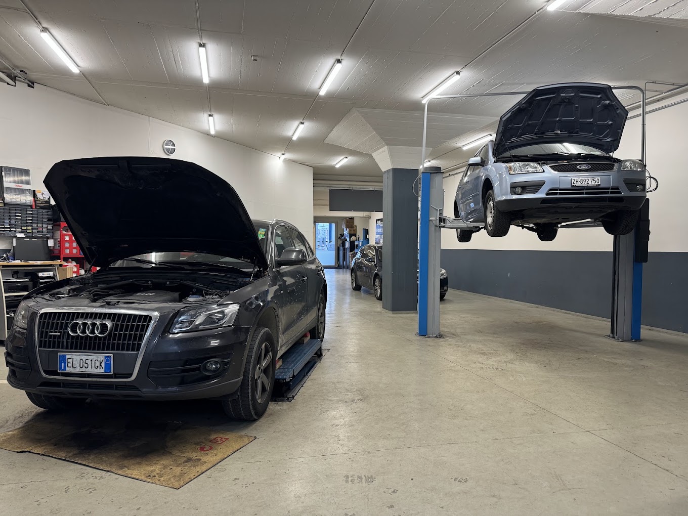 Audi Q5 und Ford Focus auf der Hebebühne im Werkstattgang